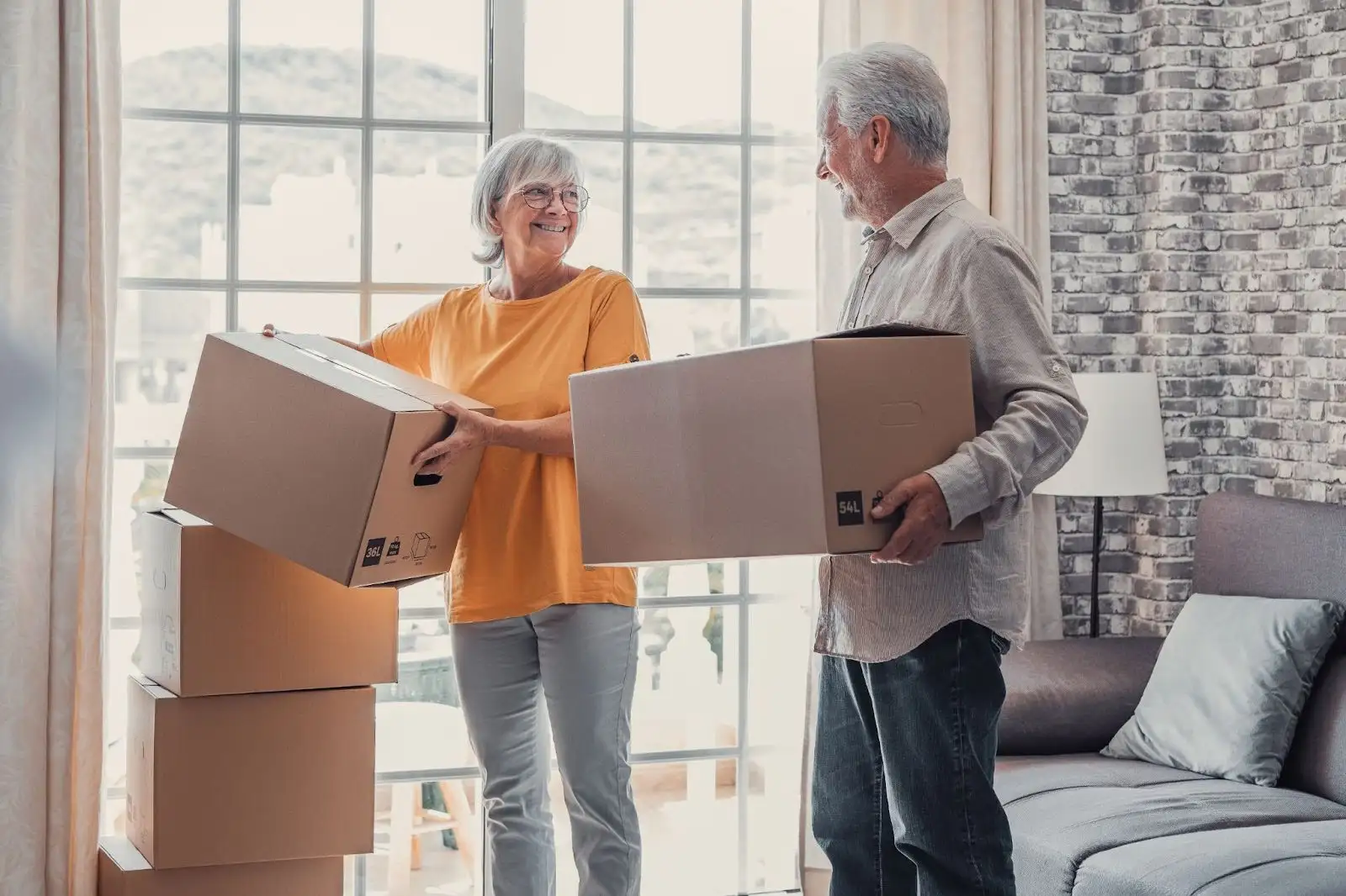 Senior couple packing moving boxes together at home, smiling during relocation.