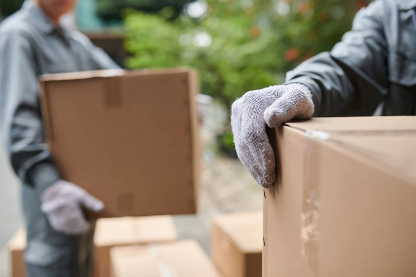 Movers handling heavy items during relocation without proper equipment and support.