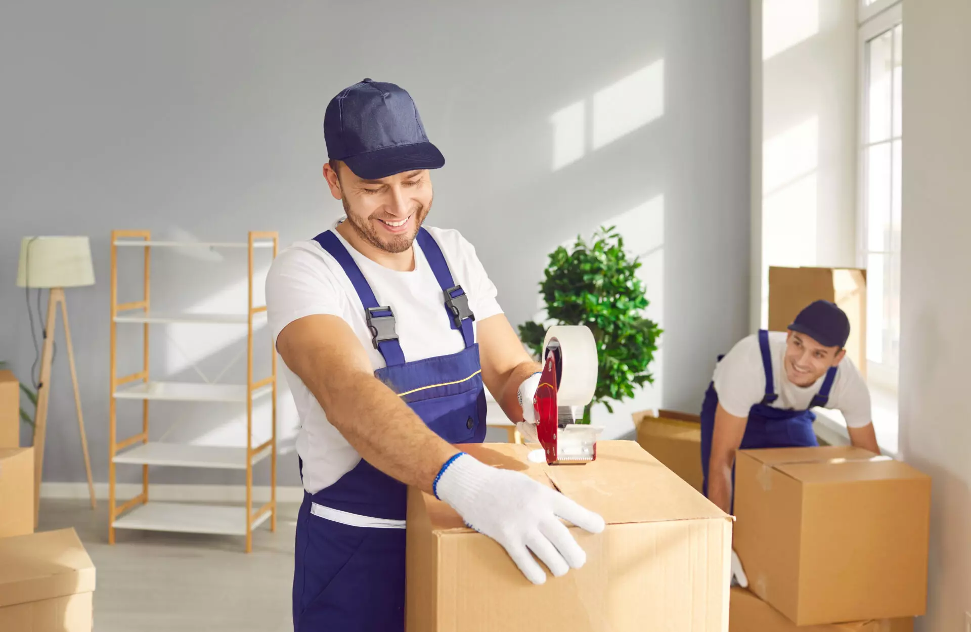 Professional movers packing and sealing boxes inside a home.